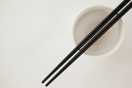 Pair of chopsticks over a bowl against white backgroundの写真素材