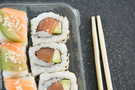 Close-up of sushi rolls with salmon in plastic containerの写真素材