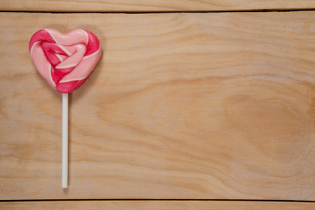 Pink heart shaped lollipop on wooden tableの写真素材