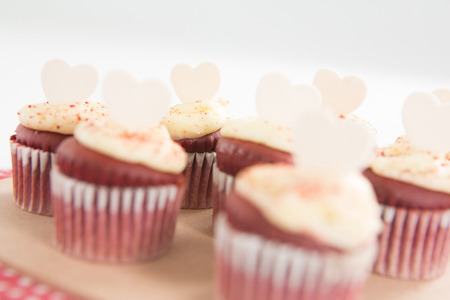 Cup cakes on heart shape paper against white backgroundの写真素材