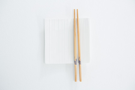 Chopstick with empty plate against white backgroundの写真素材