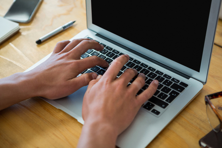 Hand of business executive using laptop at desk in officeの写真素材