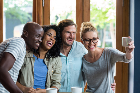 Group of friends taking a selfie from mobile phone in cafÃ©の写真素材