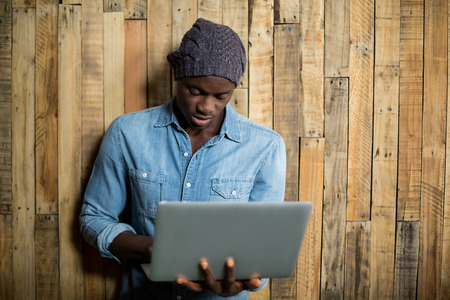 Man using laptop against wooden wall in cafÃ©の写真素材