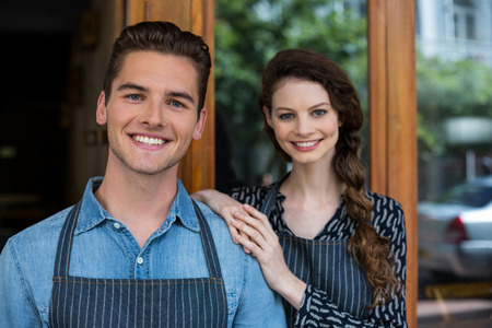 Portrait of smiling waiter and waitress standing outside the cafeの写真素材