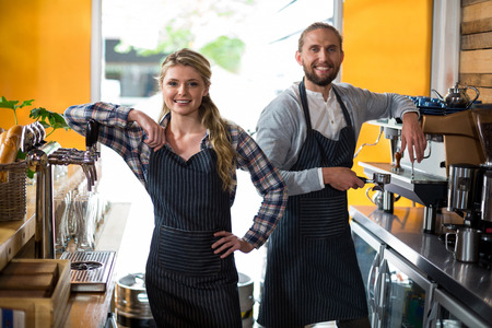 Portrait of smiling waitress and waiter working at counter in cafÃ©の写真素材
