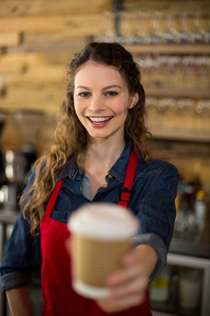 Portrait of smiling waitress serving a cup of in cafÃ©の写真素材