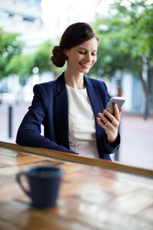 Businesswoman using mobile phone at counter in cafÃ©の写真素材