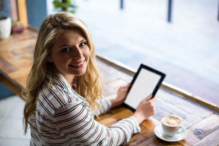 Beautiful woman using digital tablet in cafÃ©