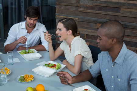 Business executives having meal on dining table in officeの写真素材