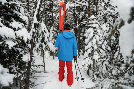 Rear view of skier walking with ski on snow covered mountainsの写真素材