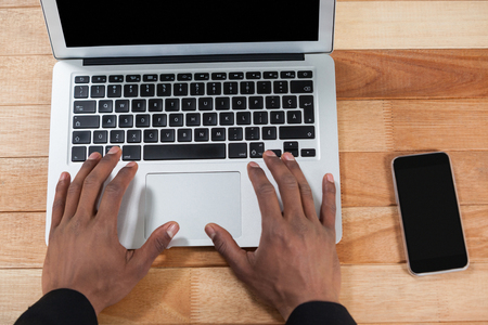 Close-up of hand using laptop at deskの写真素材