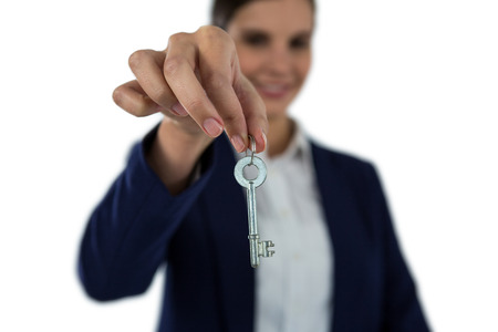 Smiling businesswoman showing new house key on white backgroundの写真素材