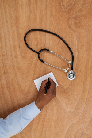 Close-up of doctor writing prescription on notepadの写真素材