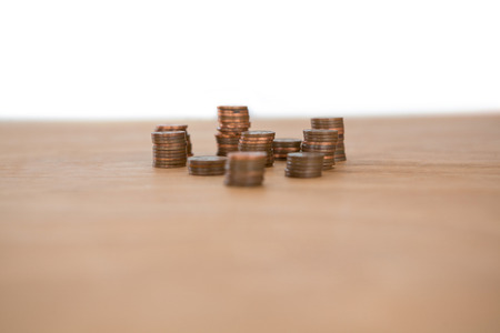 Stack of coins on table against white backgroundの写真素材