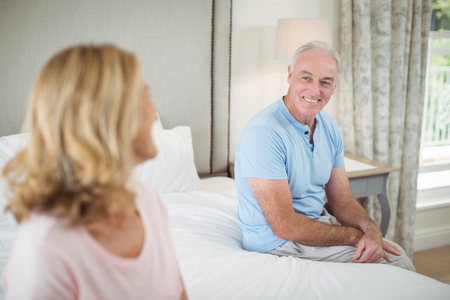Senior couple interacting with each other in bedroom at homeの写真素材