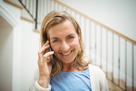 Portrait of smiling senior woman talking on mobile phone at homeの写真素材