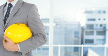 Digital composite of Architect Torso holding a cask against windowsの写真素材