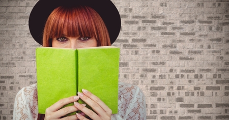 Digital composite of Woman with green book against brick wall