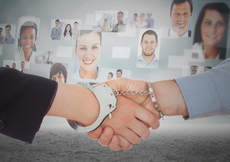 Digital composite of Handshake with handcuffs in front of sky with business people