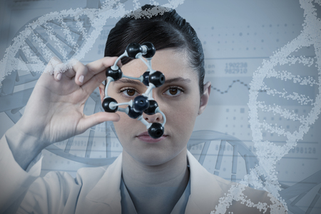 Female scientist looking through molecular model against panoramic view of information dataの写真素材