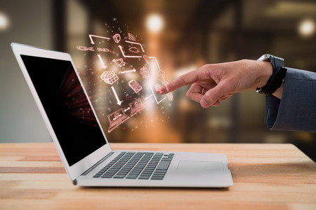 Businessman gesturing at laptop screen against blur view of office corridor and workspaceの写真素材