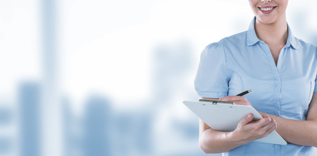 Beautiful businesswoman writing on clipboard against dental equipmentの写真素材