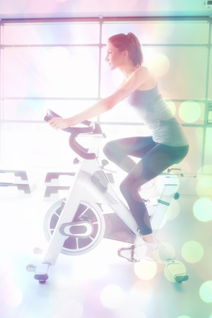 Abstract background against side view of woman energetically riding exercise bikeの写真素材