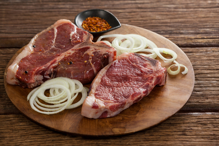 Blade chop, onions and spices on wooden round tray against wooden backgroundの写真素材