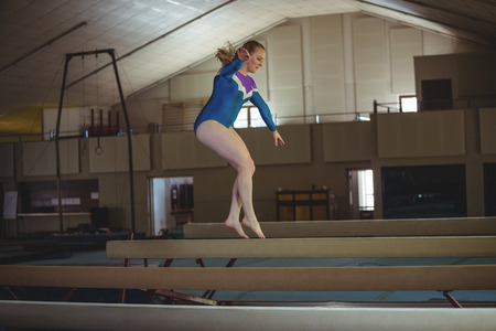 Female gymnast practicing gymnastics on the balance beam in the gymnasiumの写真素材