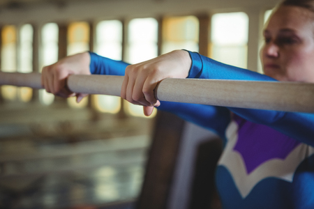 Close-up of female gymnast practicing gymnastics on the horizontal bar in the gymnasiumの写真素材