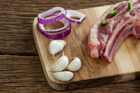 Blade chop, onions and garlic on wooden board against wooden backgroundの写真素材