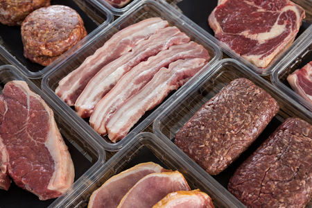 Varieties of meat in plastic boxes against wooden backgroundの写真素材