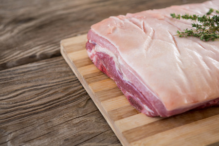 Raw beef brisket and herb on wooden tray against wooden backgroundの写真素材