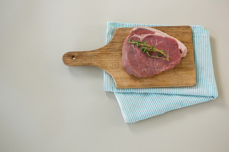 Sirloin chop on wooden tray with cooking cloth against white backgroundの写真素材