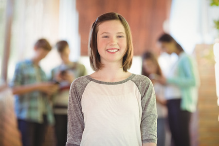 Portrait of smiling schoolgirl standing in corridor at schoolの写真素材