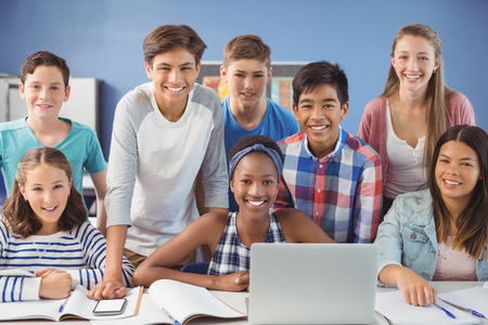 Group of students using laptop in classroom at school