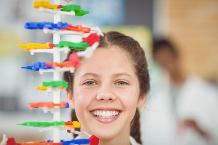 Portrait of happy schoolgirl experimenting molecule model in laboratory at schoolの写真素材