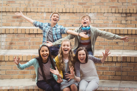 Portrait of smiling school students sitting on staircase having fun in campus at schoolの写真素材
