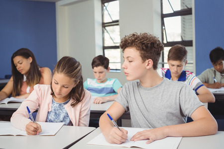 Attentive school kids doing homework in classroom at school