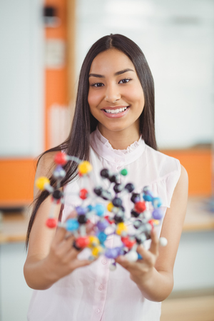 Portrait of happy schoolgirl experimenting molecule model in laboratory at schoolの写真素材