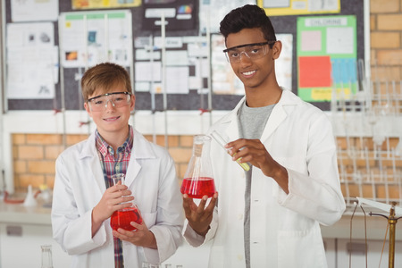 Portrait of smiling school kids doing a chemical experiment in laboratory at schoolの写真素材