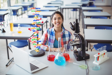 Portrait of schoolgirl sitting in laboratory at schoolの写真素材