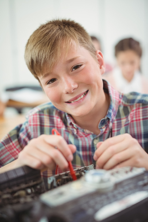 Schoolboy repairing a printer in the classroom at schoolの写真素材