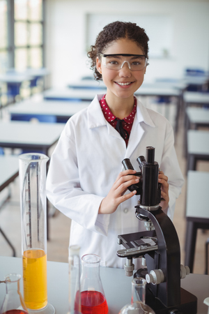 Portrait of schoolgirl experimenting on microscope in laboratory at schoolの写真素材