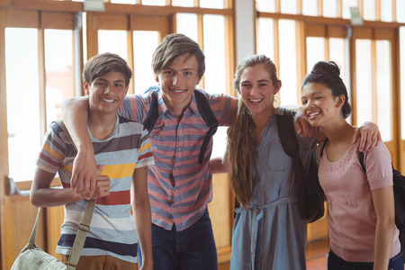 Portrait of happy students standing with arms around in campus at schoolの写真素材