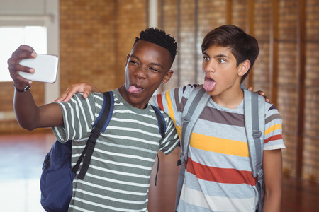 Happy schoolboys taking selfie on mobile phone in campus at schoolの写真素材