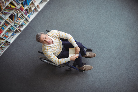 Overhead view of disabled school teacher holding book in library at schoolの写真素材