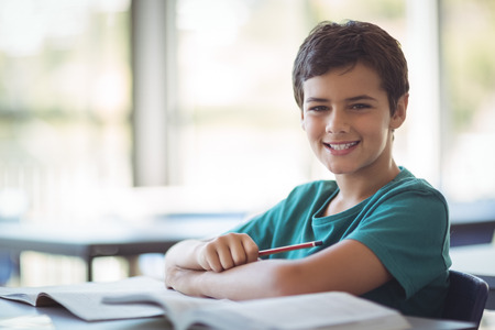 Portrait of happy schoolboy studying in classroom at schoolの写真素材