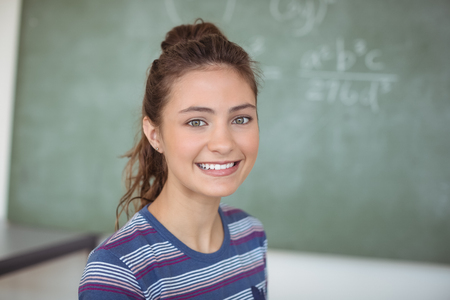 Portrait of happy schoolgirl in classroom at schoolの写真素材